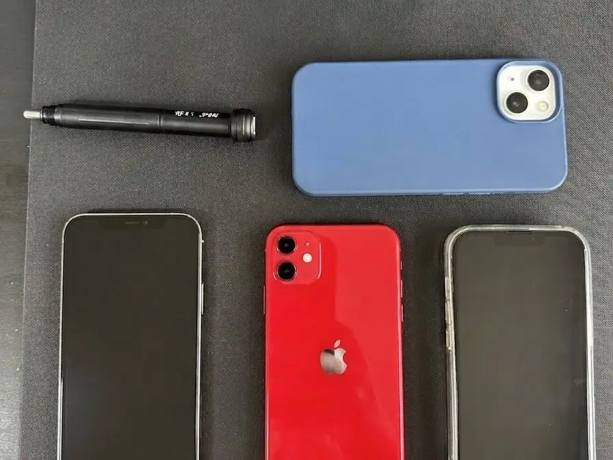 Quatre iPhone d'occasion contrôlés sur le tapis d'atelier NinjaPhone avant revente