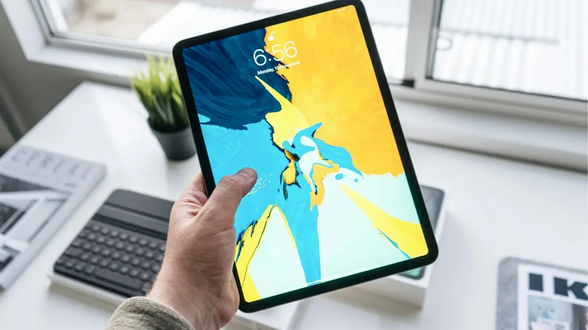 Tablette iPad tenue en main, réparation de tablette à domicile