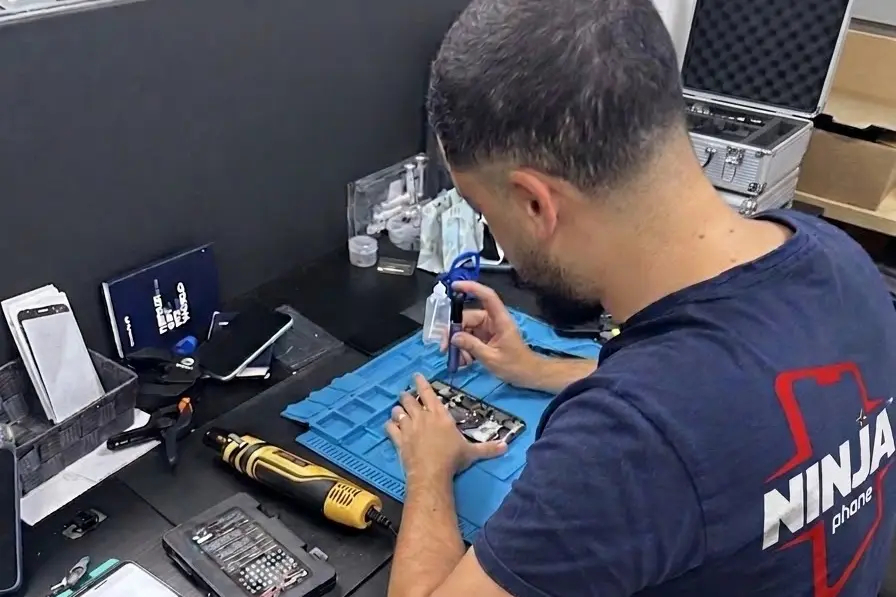Technicien NinjaPhone démontant un téléphone sur son tapis d'atelier